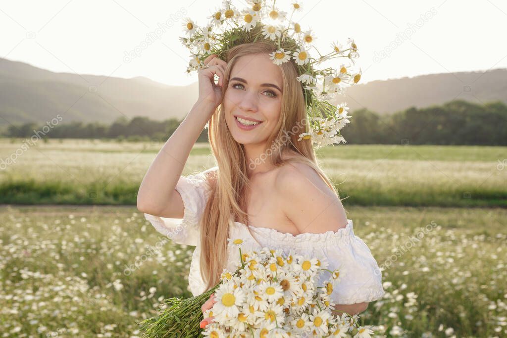 portrait of a beautiful blonde woman on meadow looking to the camera and enjoying nature spring evening outdoors. Caucasian woman relaxation in the park with daisy outside with copy space, cover