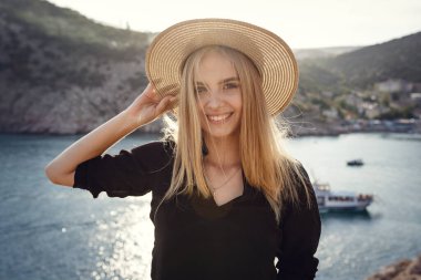 Siyah elbiseli kadın yaz denizinin üzerinde uçurumun kenarında tek başına duruyor. Seyahat yaşam tarzı konsepti.