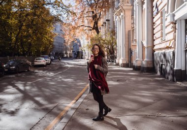 Sokakta yürüyen güzel esmer kızın portresi. Gülümsüyor. Şehir manzarası. Sıcak güneşli hava. Açık havada.