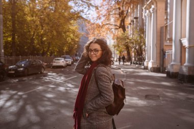 Sokakta yürüyen güzel esmer kızın portresi. Gülümsüyor. Şehir manzarası. Sıcak güneşli hava. Açık havada.