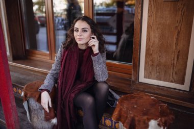 Avrupa 'nın caddesinde poz veren gri ceketli, kırmızı deri çantalı, mutlu, mutlu, mutlu, neşeli, neşeli bir kızın açık hava sonbahar portresi. Kopyala, metin için boşluk