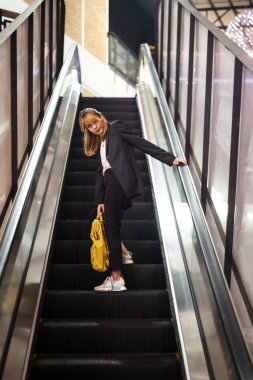 Sarı sırt çantalı yürüyen merdivendeki kadın..