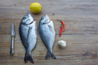 Çiğ dorado ya da sebzeli ahşap masadaki çipura balığı.