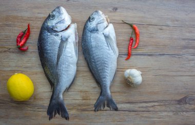 Çiğ dorado ya da sebzeli ahşap masadaki çipura balığı.