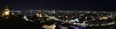 Graz 'ın şehir ışıkları ve geceleri Avusturya' daki Shlossberg Hill, Graz, Styria bölgesinde bulunan ünlü saat kulesi (Grazer Uhrturm). Panoramik görünüm.