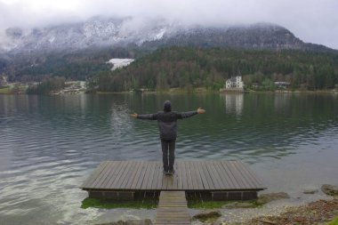 Grundlsee 'ye bakan adam, Avusturya, Styria' daki en büyük göl, ve onun güzel Villa Castiglioni 'si, sisli kış sabahı, harika dağ manzarasında batıyor.