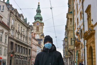 Graz/Austria - March 09, 2020: Man on city street wearing a face mask for protection against viruses during coronavirus COVID-19 and flu outbreak