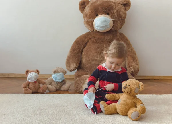 Child playing with his sick teddy bears wearing medical mask against viruses. Role playing, child playing doctor with plush toy. Children and illness concept.