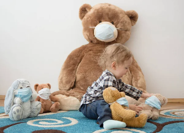 Child playing with his sick teddy bears wearing medical mask against viruses. Role playing, child playing doctor with plush toy. Children and flu, coronavirus illness concept. Selective focus