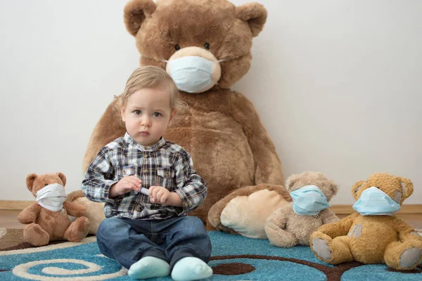 Child playing with his sick teddy bears wearing medical mask against viruses. Role playing, child playing doctor with plush toy. Children and flu, coronavirus illness concept. Selective focus