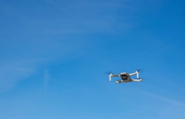 Mavi gökyüzünde uçan fotoğraf makineli beyaz dron