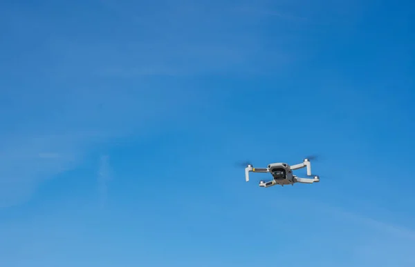 Mavi gökyüzünde uçan fotoğraf makineli beyaz dron