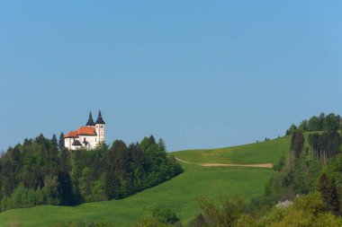 Slovenya 'nın baharda kırsalında, Slovenya' da güneşli bir bahar sabahı tepede küçük sevimli bir kilise var..