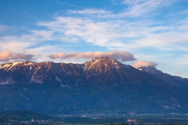 Bled Gölü 'ndeki kayanın üzerindeki eski ortaçağ şatosu ve arka planda Julian Alps, gün batımında Slovenya' daki ünlü varış yeri.