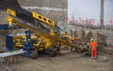 Graz / Avusturya - 09 Ekim 2019: inşaat alanında çalışan işçiler ve yerde delik açmak için kullanılan ağır iş makineleri