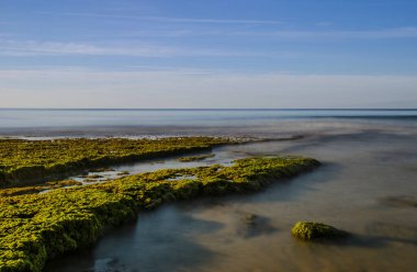 Yüksek kayalıklarla çevrili güzel Porto de Mos Sahili altın kumdan yapılmış uzun bir dil gibidir. Dalgalar alçaldığında plajın sonundaki kayalar açıkta kalır. Lagos, Batı Algarve kıyıları, Portekiz.