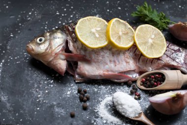 Limon, otlar ve baharatlar karanlık antika arka plan üzerinde çiğ balık