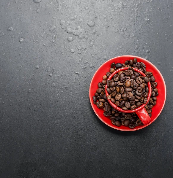 Xícara vermelha e grãos de café em um fundo preto , — Fotografia de Stock