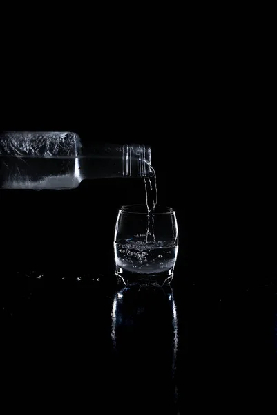 Bottle Vodka poured into a glass on black background — Stock Photo, Image