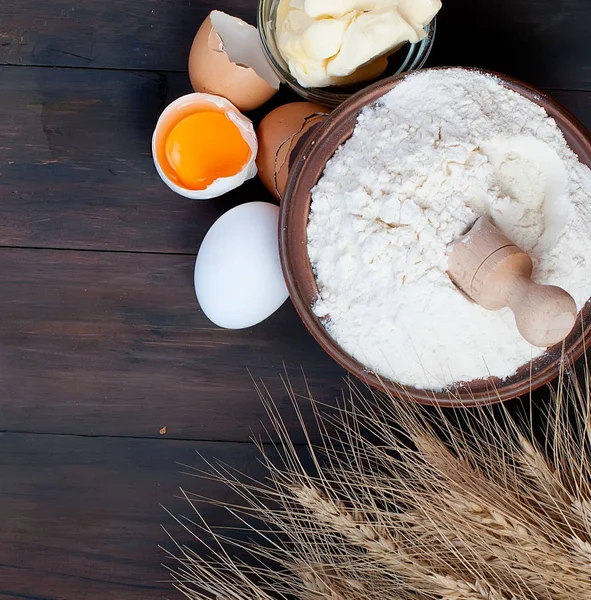 Миска с яйцами муки уши пшеницы и масла на винтажном деревянном — стоковое фото