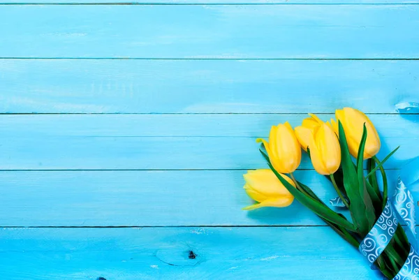 Buket gule tulipaner på en blå træbaggrund - Stock-foto