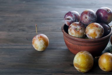 Eski ahşap masa üzerinde bir kapta bahçesinden taze Erik.