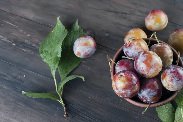 Eski ahşap masa üzerinde bir kapta bahçesinden taze Erik.