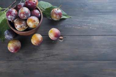 Eski ahşap masa üzerinde bir kapta bahçesinden taze Erik.