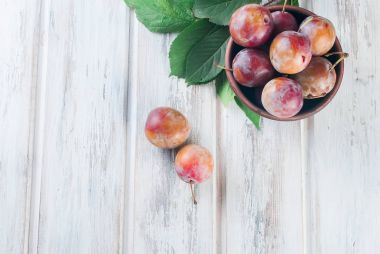 Eski ahşap masa üzerinde bir kapta bahçesinden taze Erik.