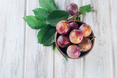 Eski ahşap masa üzerinde bir kapta bahçesinden taze Erik.