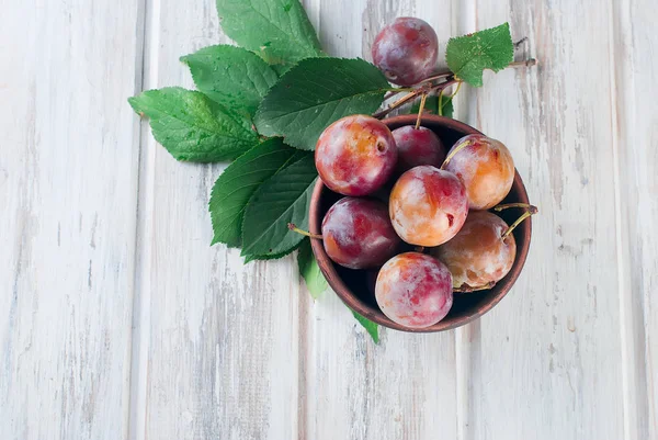 Eski ahşap masa üzerinde bir kapta bahçesinden taze Erik.