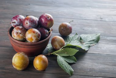 Eski ahşap masa üzerinde bir kapta bahçesinden taze Erik.