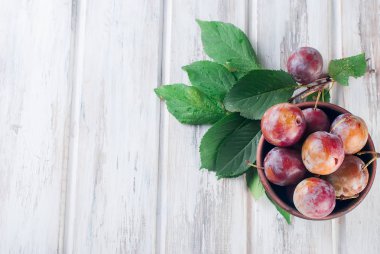 Eski ahşap masa üzerinde bir kapta bahçesinden taze Erik.