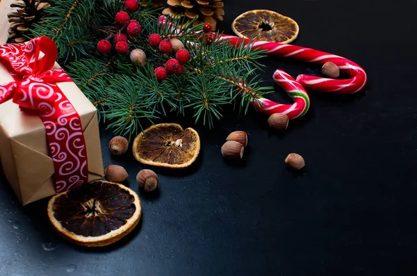 Caja de regalo atada con una cinta roja, ramas de abeto, dulces —  Fotos de Stock