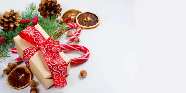 Hediye kutusu bağlı bir kırmızı kurdele, çam dalları, şeker 