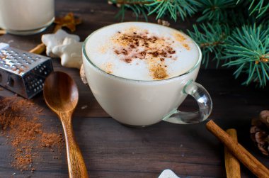 Fincan sıcak kahve latte, tarçın, kurabiye ve çam dalları. 