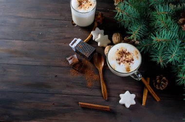 Fincan sıcak kahve latte, tarçın, kurabiye ve çam dalları. 