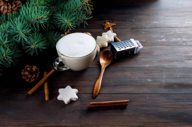 Fincan sıcak kahve latte, tarçın, kurabiye ve çam dalları. 