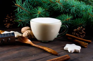 Fincan sıcak kahve latte, tarçın, kurabiye ve çam dalları. 