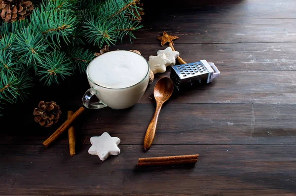 Fincan sıcak kahve latte, tarçın, kurabiye ve çam dalları. 