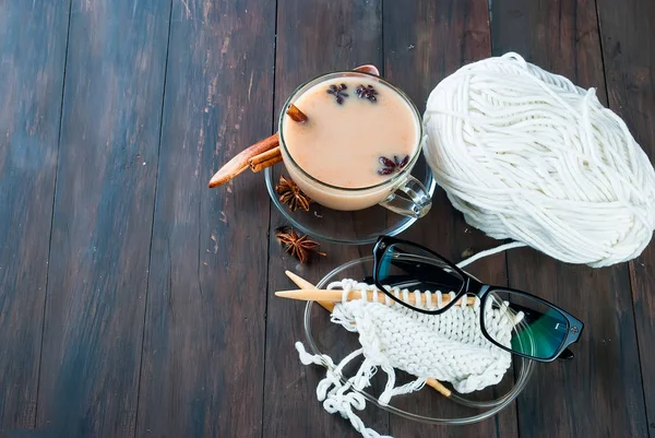 Kop te med mælk, strikketråde og briller på et træ - Stock-foto