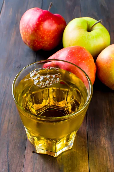 Apple juice in a glass and a ripe apples on a wooden table — Stock Photo, Image