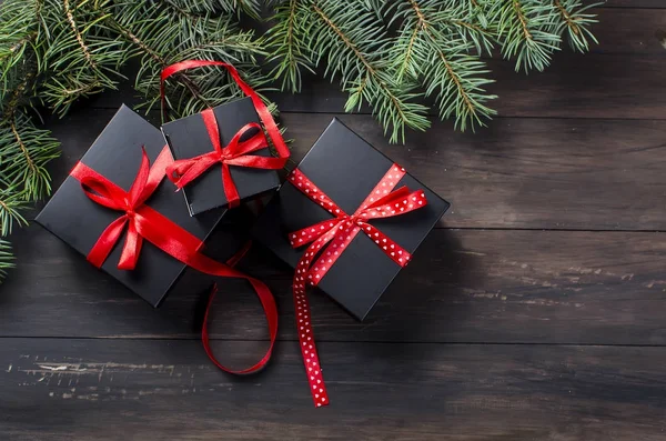 Чорна різдвяна подарункова коробка з червоною стрічкою та ялиновими гілками — стокове фото