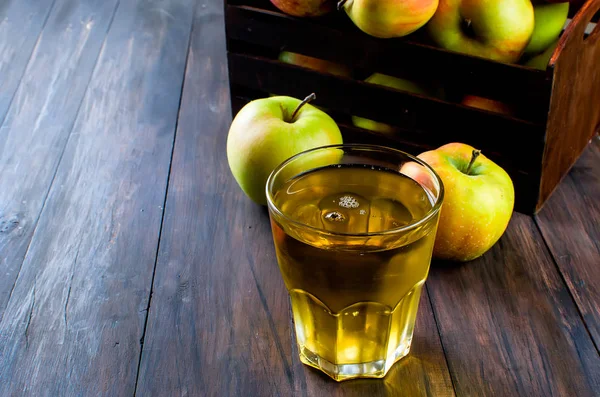 Apfelsaft im Glas und reife Äpfel auf einem Holztisch — Stockfoto