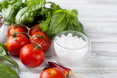 Domates ve bir beyaz tahta backgrou üzerinde taze yeşil fesleğen demet