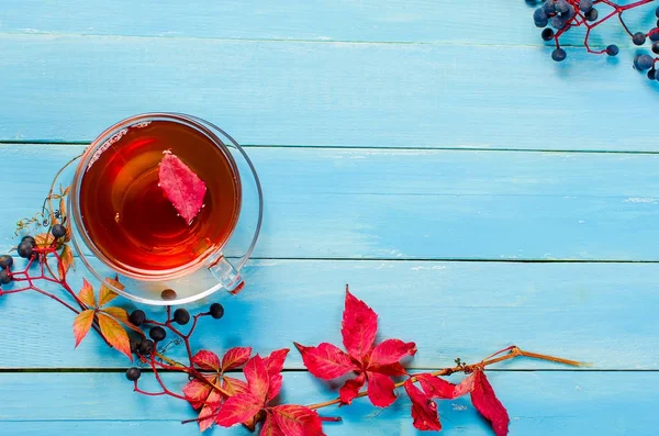 Podzimní listí a šálek čaje na dřevěný stůl — Stock fotografie