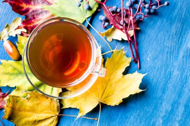 Sonbahar yaprakları ve ahşap masa üzerinde çay 