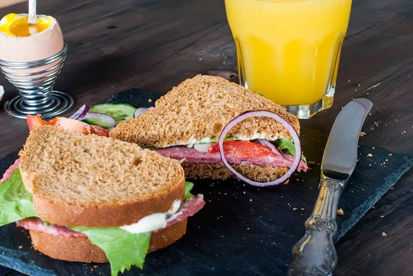 Sándwich, huevo, taza de café y un vaso de jugo para el desayuno — Foto de Stock