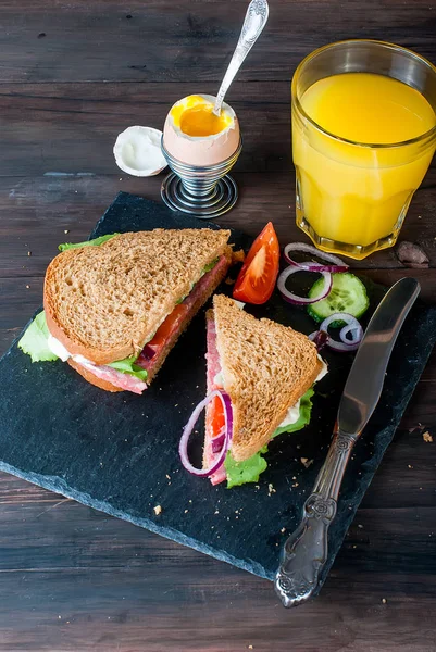 Sándwich, huevo, taza de café y un vaso de jugo para el desayuno — Foto de Stock