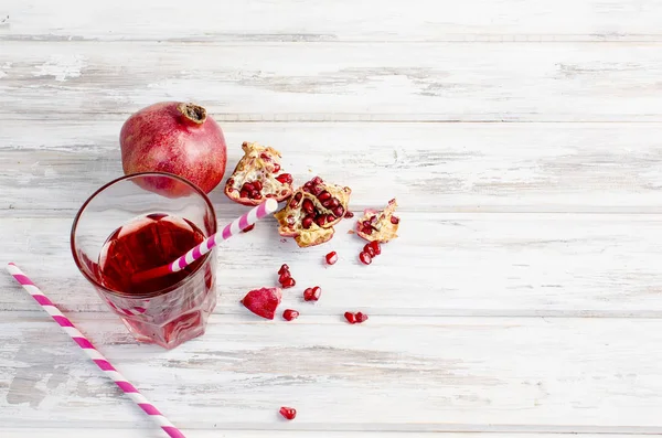 Granatäpplejuice i glas och granatäpplen på vit trä bac — Stockfoto